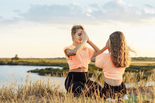 Photo young mother with her daughter making yoga outdoors