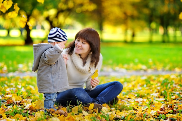 Giovane madre con il suo piccolo neonato divertendosi nel parco di autunno