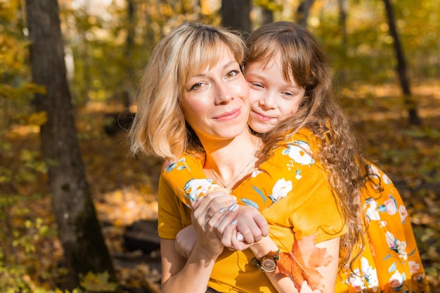秋の公園で彼女の小さな娘と若い母親。秋のシーズン、子育てと子供のコンセプト。