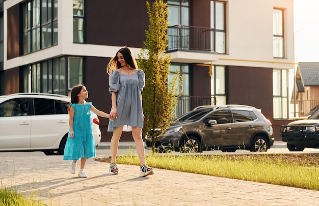 Young mother with her little daughter walking near the buildings