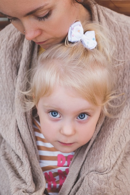 A young mother with her little daughter wrapped in her mother's jacket. High quality photo