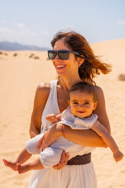 Young mother with her son very happy in the dunes of the Corralejo Natural Park, Fuerteventura, Canary Islands. Spain