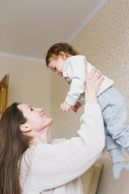 ソファーに座って手に小さな子供を持つ若い母親。娘を持つ若い女性