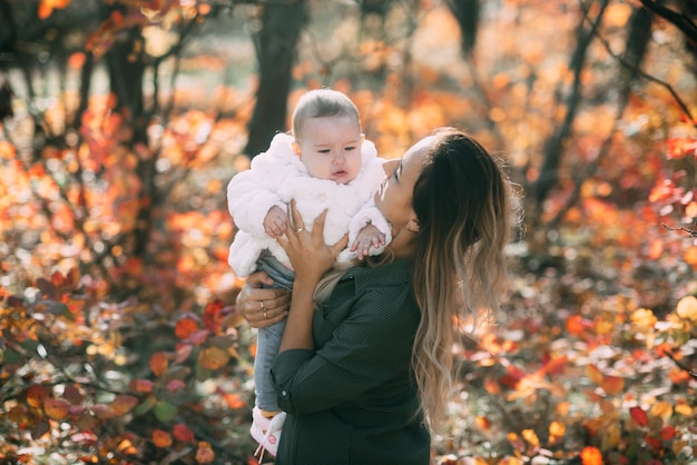 Young mother with little girl in autumn forest