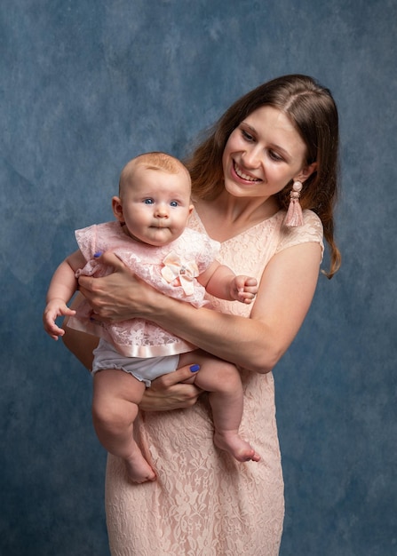 Молодая мама с длинными волосами в легком платье держит на руках новорожденную дочь Любовь мамы