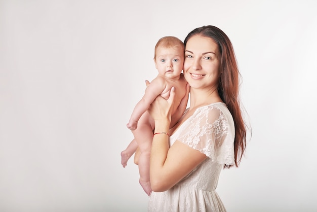 молодая мама с натуральным макияжем держит ребенка на руках