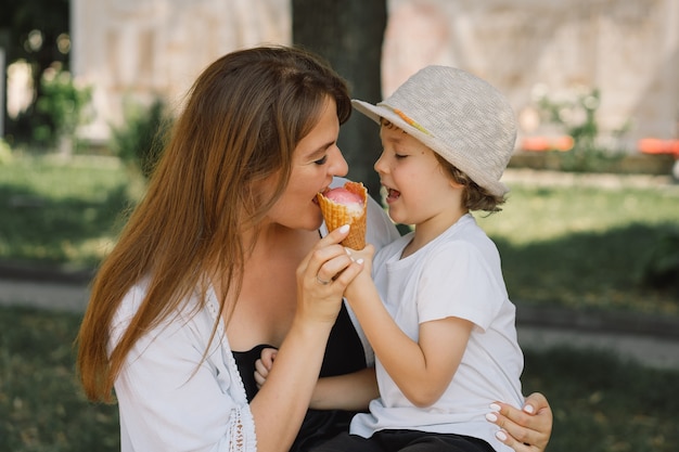 アイスクリームの夏の食べ物と夏の時間を食べる夏の屋外で小さな男の子と若い母親