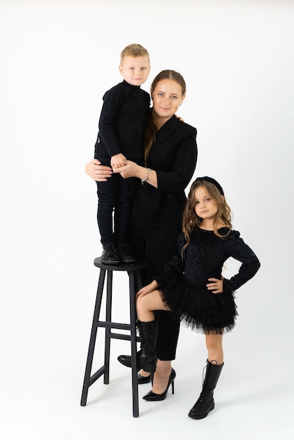 A young mother with a son and daughter in black clothes is looking at the camera