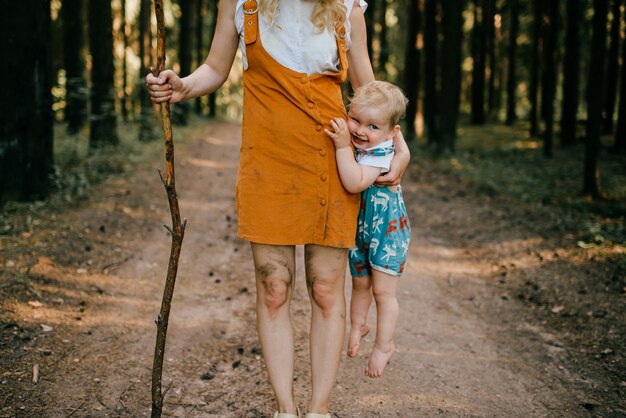 森の中で息子を抱きしめて棒で若い母親