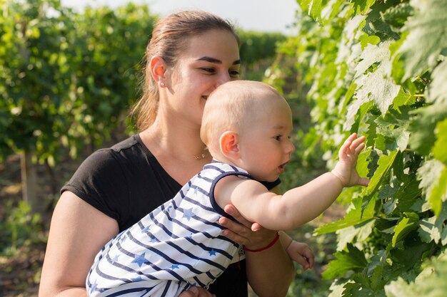 A young mother with a toddler in a vineyard in the summer