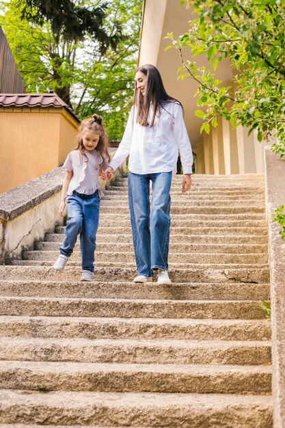 A young mother with a young daughter comes down the stairs. a\
woman holds a girl\'s hand and talks to her.