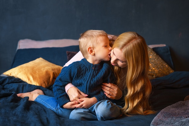 A young mother with a young son sitting on the bed in an embrace