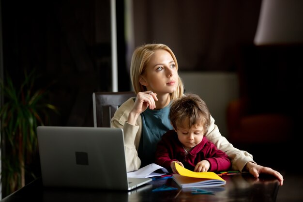 Young mother works at a computer at home with her child