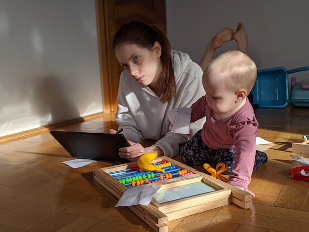 young mother works online from home child sits next to her