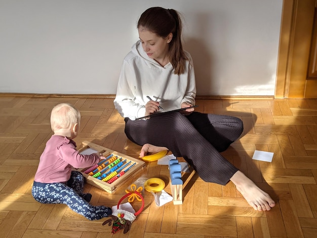 Foto giovane madre lavora online da casa il bambino si siede accanto a lei