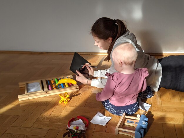 Foto giovane madre lavora online da casa il bambino si siede accanto a lei