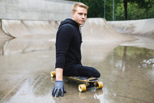 Ragazzo disabile giovane e motivato con un longboard in uno skatepark