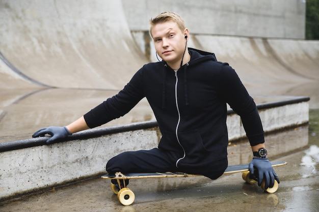 Ragazzo disabile giovane e motivato con un longboard in uno skatepark