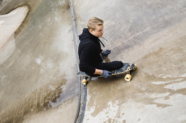 Ragazzo disabile giovane e motivato con un longboard in uno skatepark