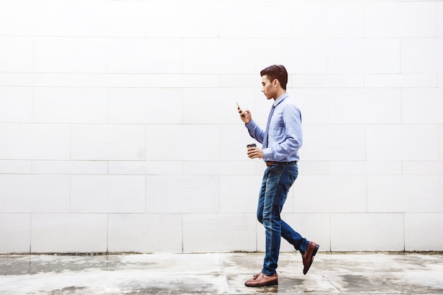 Молодая мотивация Бизнесмен, используя смарт-телефон во время прогулки на улице