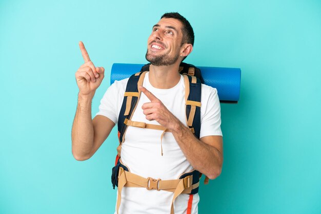 Young mountaineer caucasian man with a big backpack isolated on blue background pointing with the index finger a great idea