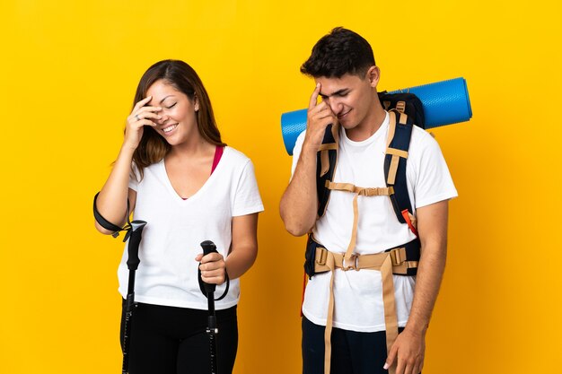 Young mountaineer couple with a big backpack on yellow laughing