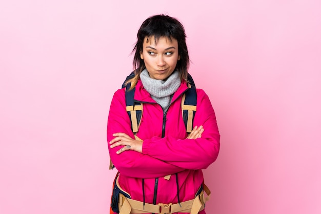 Young mountaineer girl with a big backpack over isolated pink thinking an idea