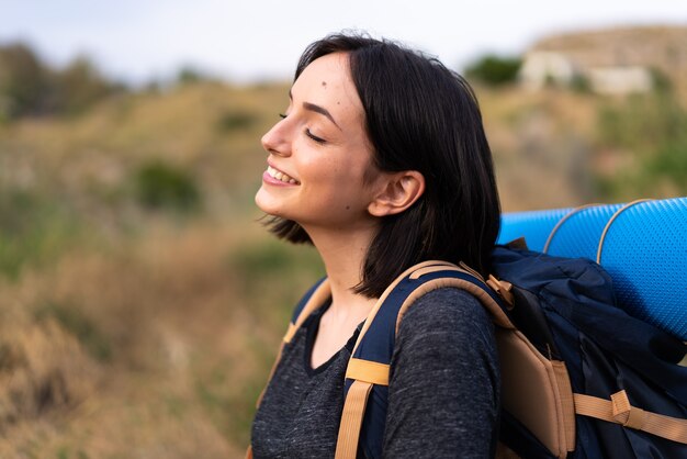 屋外で大きなバックパックを持つ若い登山家の女の子