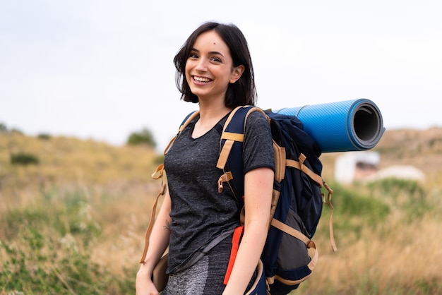 Young mountaineer girl with a big backpack at outdoors