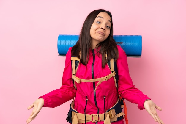 Young mountaineer girl with a big backpack over pink smiling