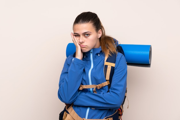 Young mountaineer girl with a big backpack unhappy and frustrated