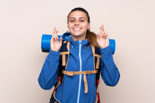 Young mountaineer girl with a big backpack with fingers crossing