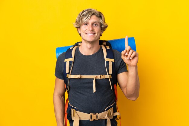 Young mountaineer man over isolated yellow pointing up a great idea