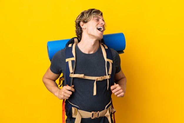 Young mountaineer man over isolated yellow wall laughing