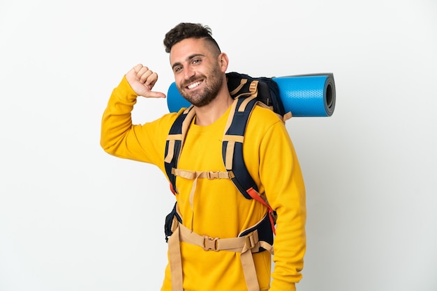 Young mountaineer man with a big backpack over isolated background proud and self-satisfied