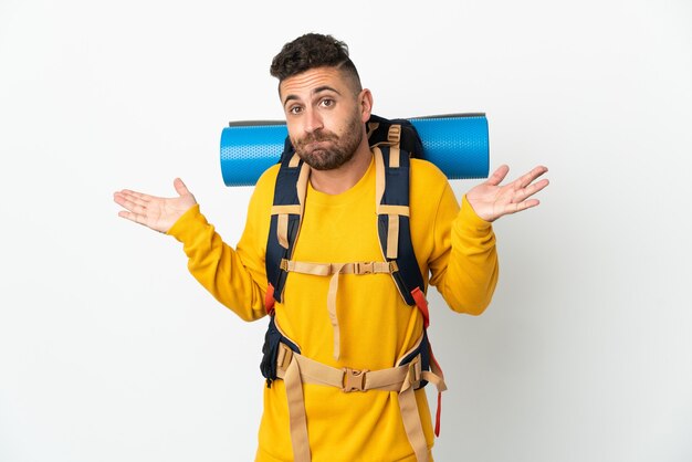 Young mountaineer man with a big backpack over isolated having doubts while raising hands