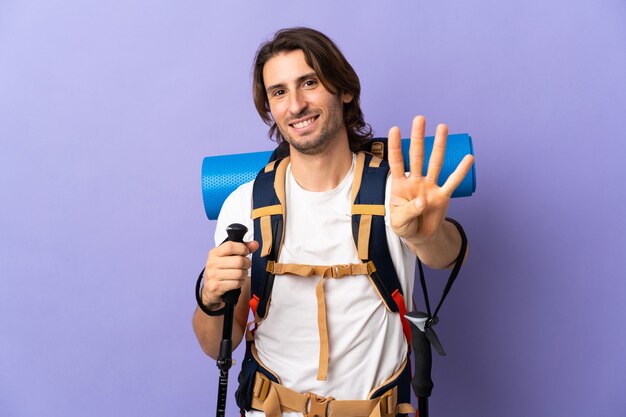 Young mountaineer man with a big backpack over isolated wall happy and counting four with fingers