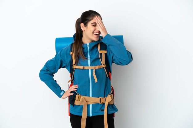 Молодой альпинист с большим рюкзаком над изолированной стеной, много улыбаясь