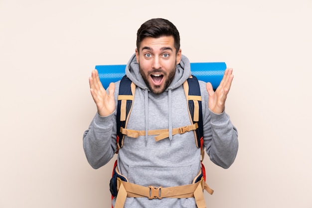 Young mountaineer man with a big backpack over isolated wall