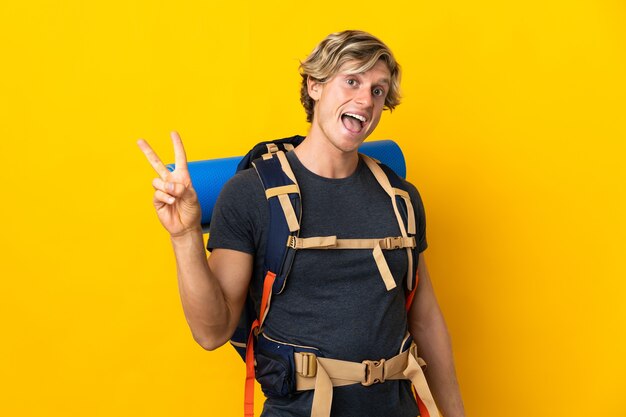 Young mountaineer man over yellow smiling and showing victory sign