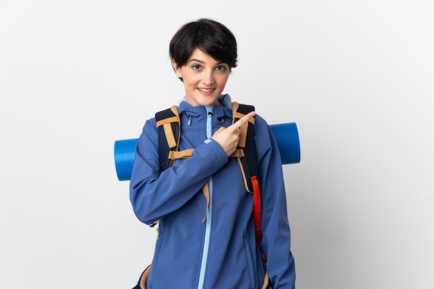 Young mountaineer woman over isolated wall pointing to the side to present a product