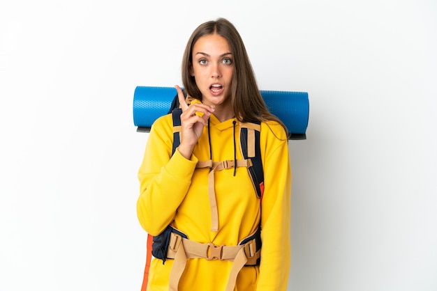 Young mountaineer woman with a big backpack over isolated white background intending to realizes the solution while lifting a finger up