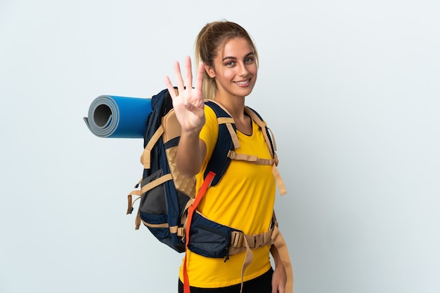 Young mountaineer woman with a big backpack posing isolated against the blank wall