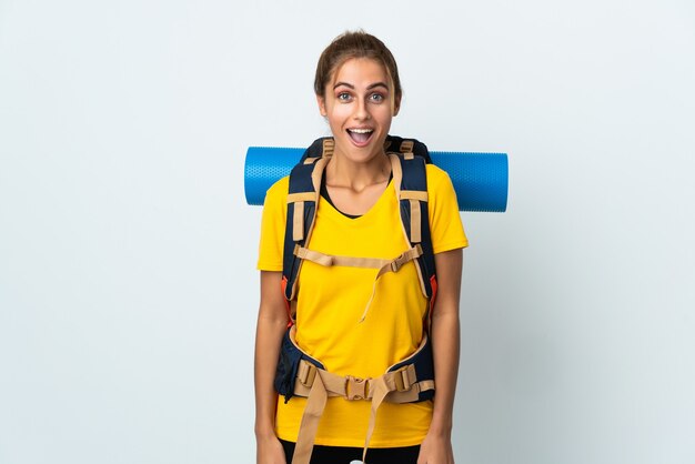 Young mountaineer woman with a big backpack on white with surprise facial expression