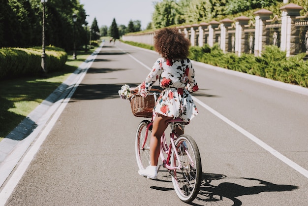 Young Mulatto In Flower Dress Is Cycling Outside.