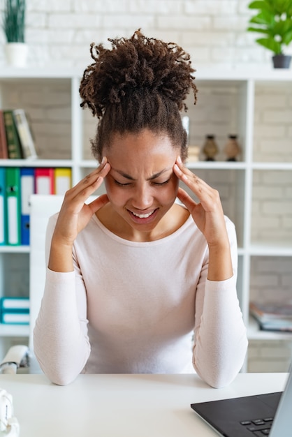 Young mulatto woman have a chronic headache, touching temples to relieve pain, tired fatigued lady