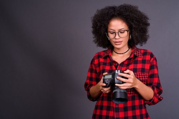 Photo young multi ethnic african american hipster woman with afro hair against gray wall