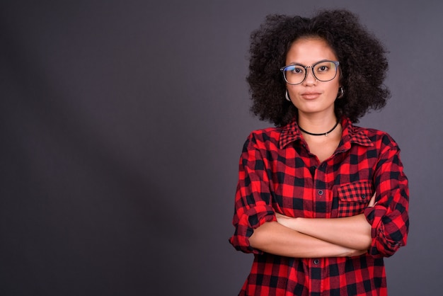  young multi ethnic African American hipster woman with Afro hair against gray wall