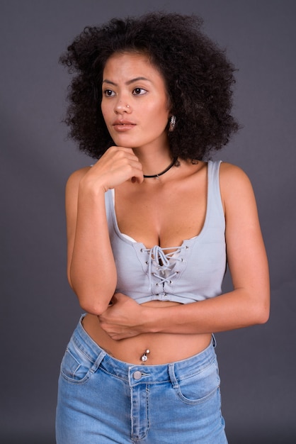 молодая многоэтническая афроамериканка с афро-волосами у серой стены