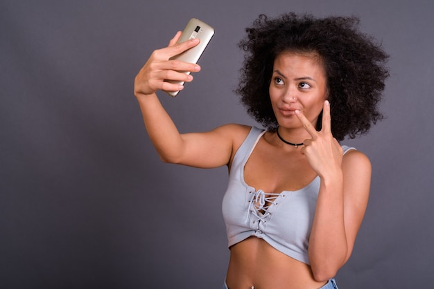  young multi ethnic African American woman with Afro hair against gray wall